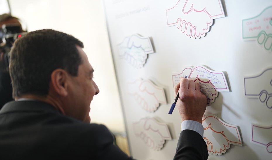 Juanma Moreno signs a panel placed at the congress.